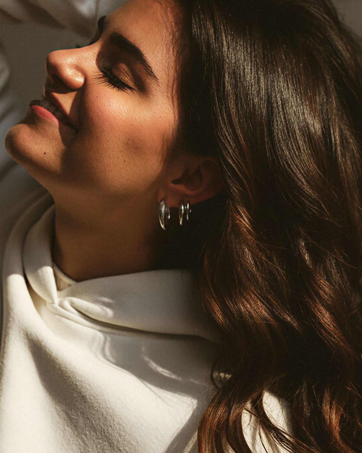 Person smiling, wearing silver hoop earrings