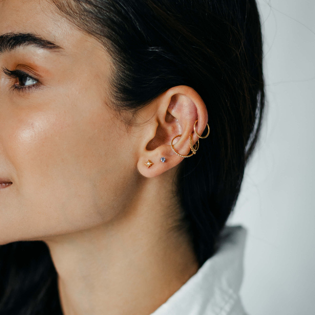 Classic, Siren, and Eternity Cartilage Hoop and North Star and Sapphire Nap Earrings (Gold) on model