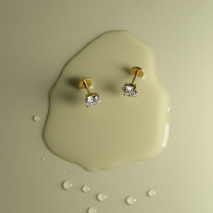 Gold earrings with clear stones on a beige background