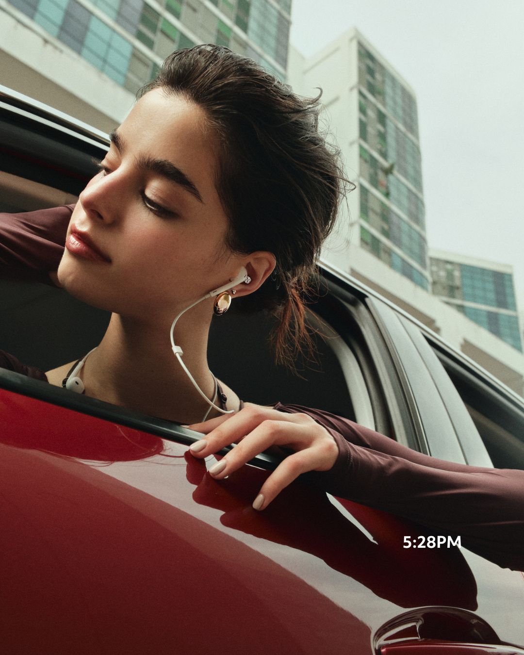 Model wearing Oversized Oval Studs in gold, leaning out of a car window