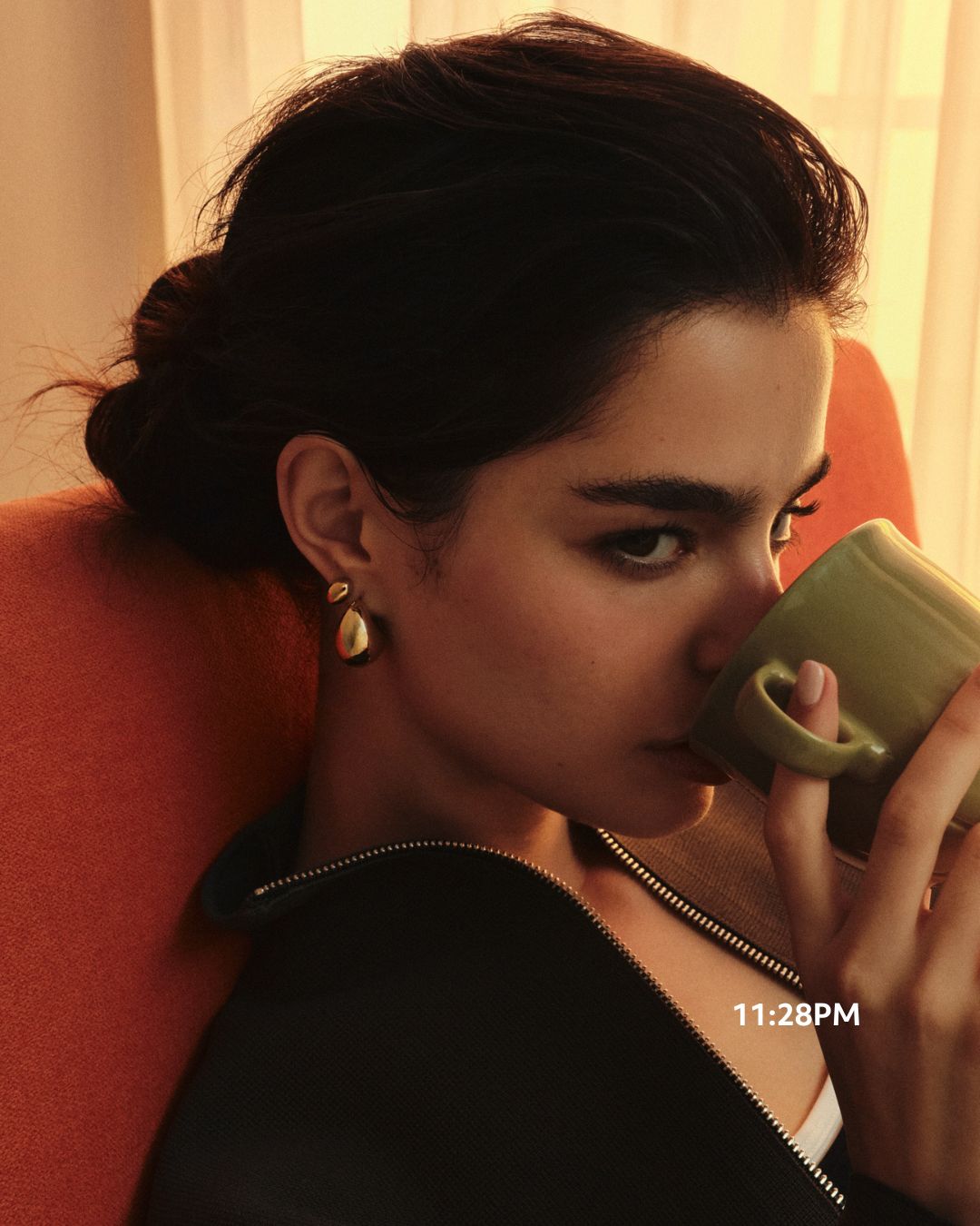 Model wearing Mini Dewdrop Hoops in gold, holding a mug
