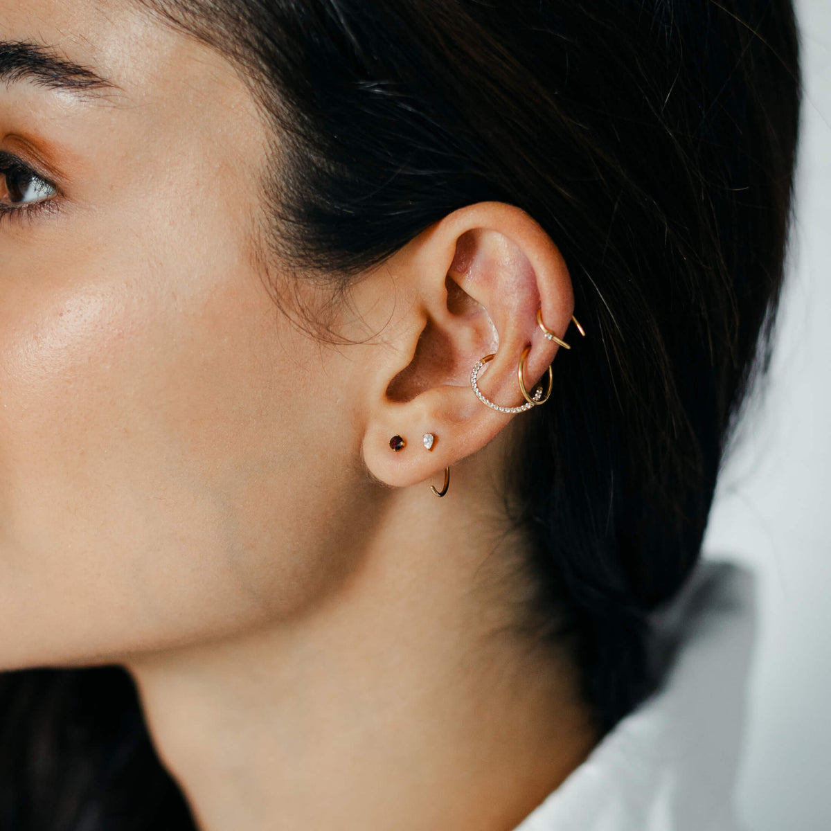 Shooting Star Open Hoop, Classic and Cosmic Cartilage Hoop, Pear Open Huggie Hoop and Garnet Nap Earrings (Gold) on model