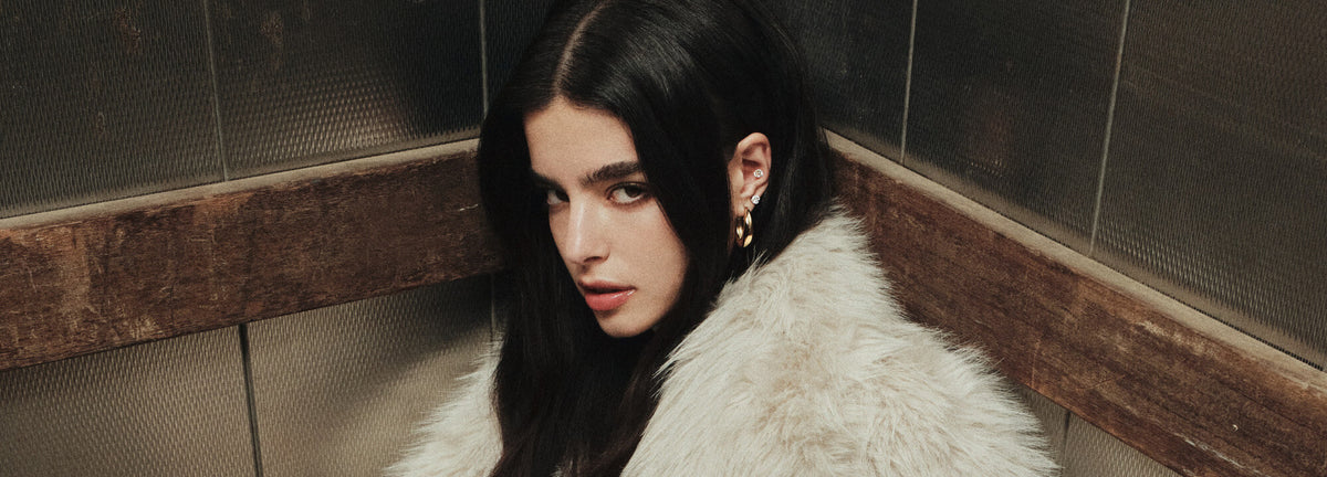 Woman with long dark hair wearing a white fur coat in an elevator